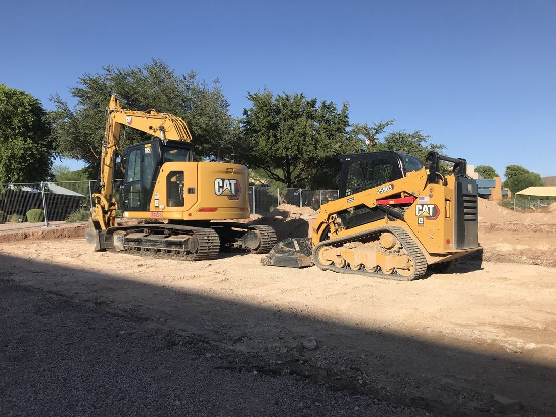 Excavator and skid steer staged at a fenced residential job site